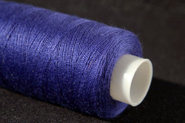 Bobbin of blue threads on dark background Shallow depth of field