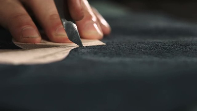 The master makes shoes in the workshop. Cutting shoe leather as template, clicking the upper. Indoor. 4K 60fps