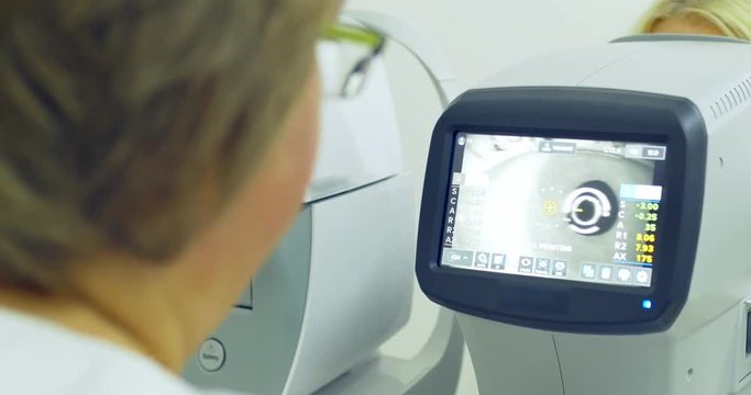 Woman doctor working with the refractometer machine. Close-up of ophthalmology technology