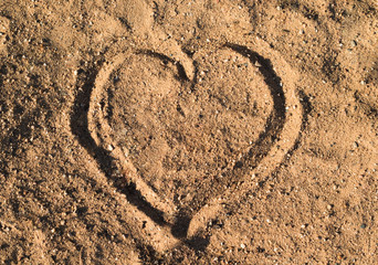 Heart in the sand on the beach at summer sunset