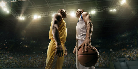 Two black basketball players on big professional arena before the game. Two teams. Players collided face to face. Player holds a ball