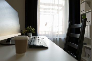Cup of coffee in office next to computter. Working late concept