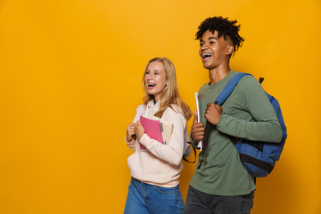 Photo of teenage people guy and girl 16-18 wearing backpacks smiling and holding exercise books...