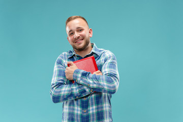 Businessman hugging laptop. Love to computer concept. Attractive male half-length front portrait, trendy blue studio backgroud. Young emotional bearded man. Human emotions, facial expression concept.