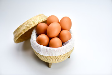 Brown eggs in the basket on a white background.