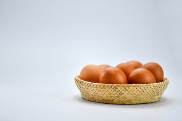 Brown eggs in the basket on a white background.