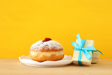 Image of jewish holiday Hanukkah with present box and donut on the table.