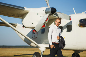 A young man stands near an airplane. Small aircraft for private travel