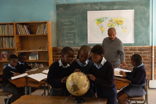 Schoolkids using globe in classroom