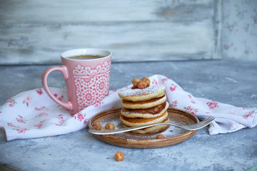 pancakes sprinkled with nuts hazelnuts on a plate with a napkin on a concrete background
