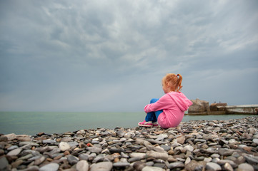 Girl sitting on a rocky beach with knees