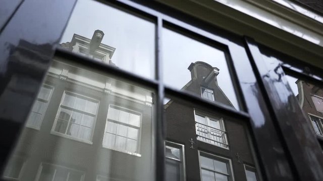 Close-up window with reflected building in glass. Houses in dutch style with elements of Art Nouveau, classicism and industrial design. Amsterdam, Netherlands