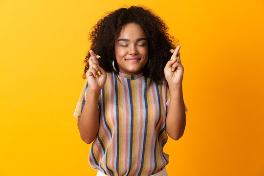 Excited young african cute girl posing isolated over yellow background make hopeful gesture.