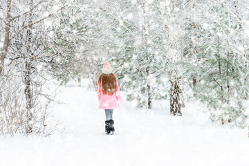 Girl walking in the winter forest, backview