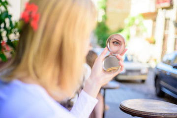 Check if everything is right. Woman looking in her pocket mirror selective focus defocused...