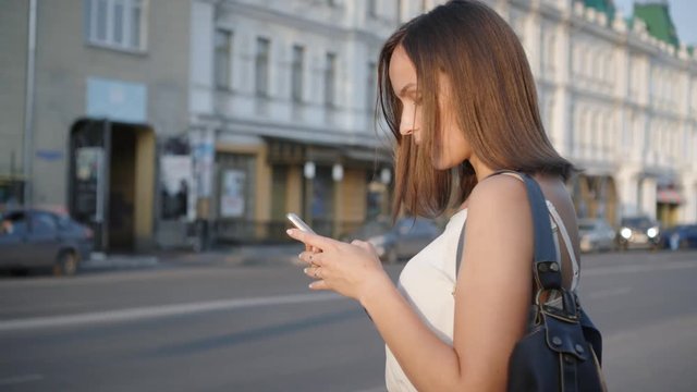 Attractive woman using smartphone in city street looked and smiled at the camera.