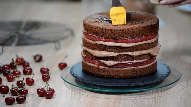 Preparation of chocolate cake with cherries. The cake is soaked with sweet syrup for moisture