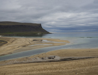 view on pink beige sand beach and green grass and stone shore in
