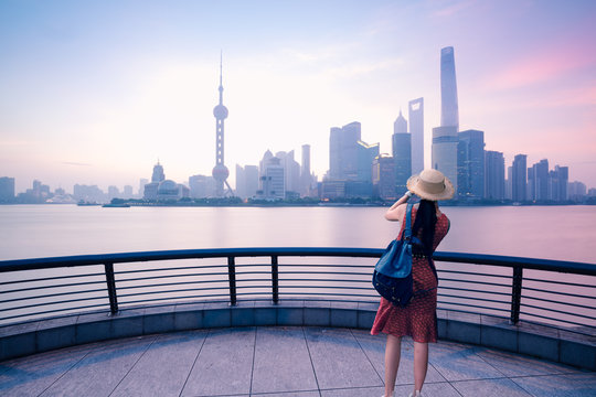 woman traveler taking photo with smart phone at the bund in shanghai, china