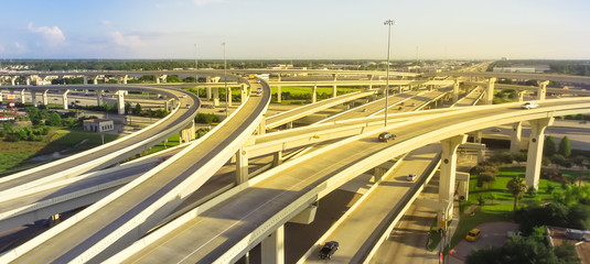 Panorama horizontal aerial view massive highway intersection, stack interchange blue sky in Houston, Texas, USA. Elevated road junction overpass, five-level freeway carry heavy rush hour traffic