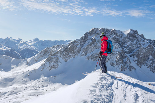 Male ski tourer enjoying the view on a summit in the alps