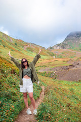 Beautiful happy young woman in mountains in the background of fog