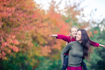 Little girl with mom outdoors in park at autumn day