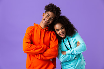 Young cute african couple posing isolated over violet background.