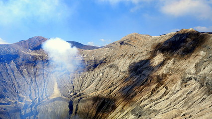 Kraterrand des Vulkans Bromo mit aufsteigendem Rauch in den blauen Himmel in Java © globetrotter1