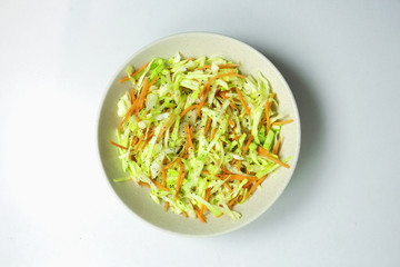 Cabbage salad with carrots, on a plate on a white background