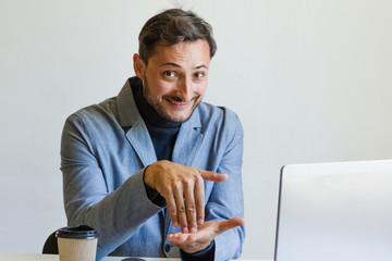 A man with an unshaven face in his jacket smiles and gesticulates
