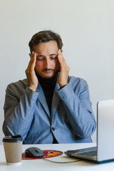 a man with an unshaven face in his jacket rubs the fingers of his head whiskey