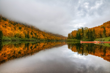 Quiet and calm Jacques Cartier river under vibrant colors of the Fall, Quebec, Canada