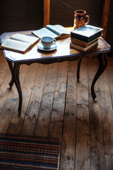 Antique wooden table with books and a cup on the table