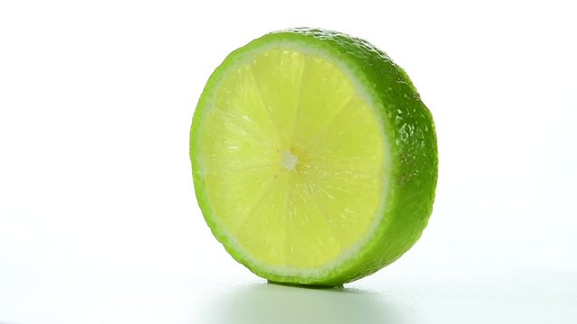 Fresh green lime slice is slowly rotating in the studio