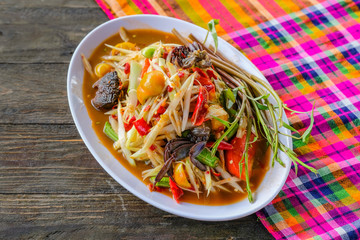 Som Tam (Spicy Papaya Salad) with salted crab, on wooden table ( Thai food)