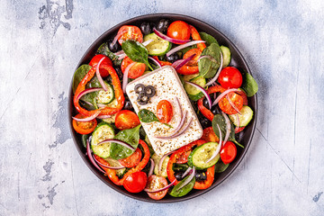Greek salad of fresh cucumber, tomato, sweet pepper, spinach, red onion, feta cheese and olives