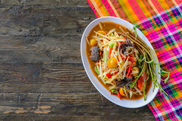 Som Tam (Spicy Papaya Salad) with salted crab, on wooden table ( Thai food)