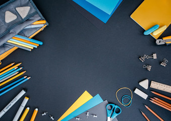 Top view of various school supplies on black background with copy space. Preparing a kid for school concept.