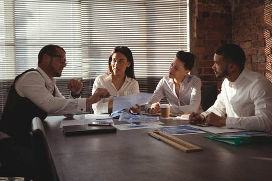 Executives discussing over document in conference room
