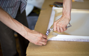 hands stretching the canvas on the stretcher
