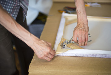 hands stretching the canvas on the stretcher