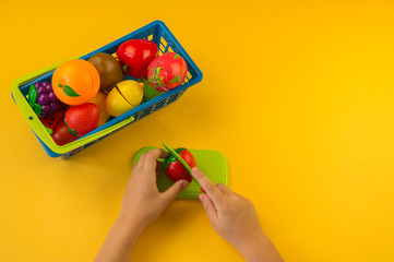 A child cuts a plastic fruit on a board