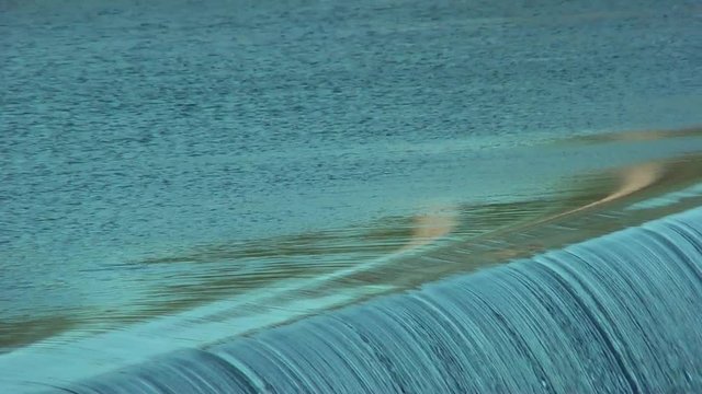 Flowing water through the dam. Waterfall.