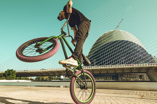 Guy tricking a bmx bike down the street