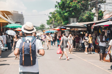 Man traveling backpacker with hat, Asian traveler standing at Chatuchak Weekend Market, landmark and popular for tourist attractions in Bangkok, Thailand. Travel concept