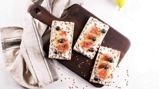 Canape or crostini with multigrain  crispread with cream cheese and fresh fig slices on a wooden board. Delicious appetizer ideal as an aperitif.