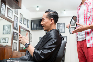 Satisfied client sitting in chair showing thumb up sign in salon