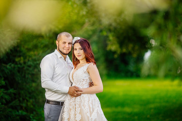 Bride and groom in a park kissing. Young wedding couple newlyweds bride and groom at a wedding in nature green park near lake. Walking and kissing photo portrait. Before wedding ceremony.