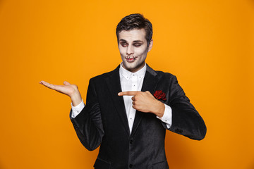 Photo of terrifying zombie bridegroom wearing classical suit and halloween makeup holding copyspace...